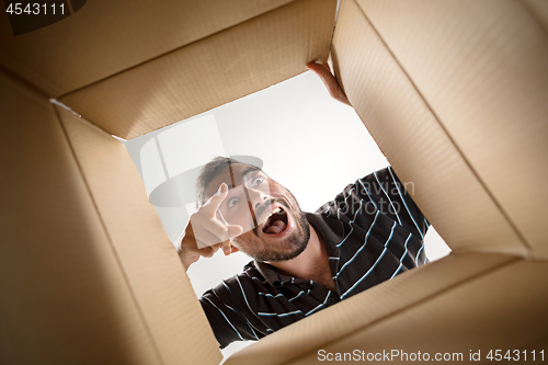 Image of Man unpacking and opening carton box and looking inside