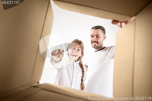 Image of dad with daughter unpacking and opening carton box and looking inside