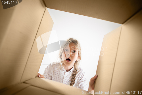 Image of The girl unpacking and opening carton box and looking inside