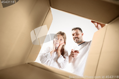 Image of dad with daughter unpacking and opening carton box and looking inside