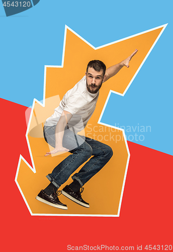 Image of Freedom in moving. handsome young man jumping against orange background