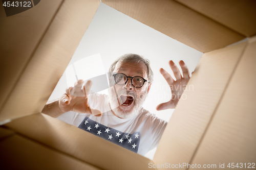 Image of Man unpacking and opening carton box and looking inside