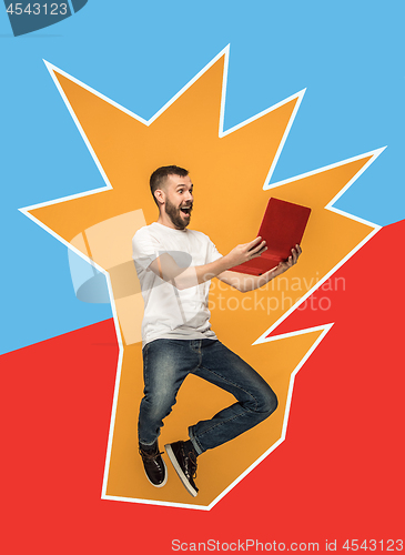 Image of Image of young man over orange background using laptop computer while jumping.