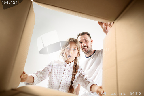 Image of dad with daughter unpacking and opening carton box and looking inside