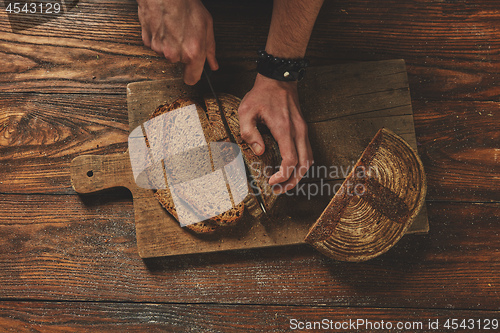 Image of Baker man slices bread