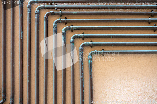 Image of some copper tubes outside on a wall