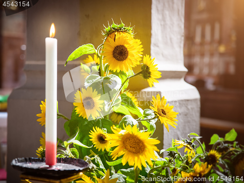 Image of sunflowers with a burning candle in a church