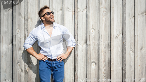 Image of bearded man with sunglasses at a wooden wall