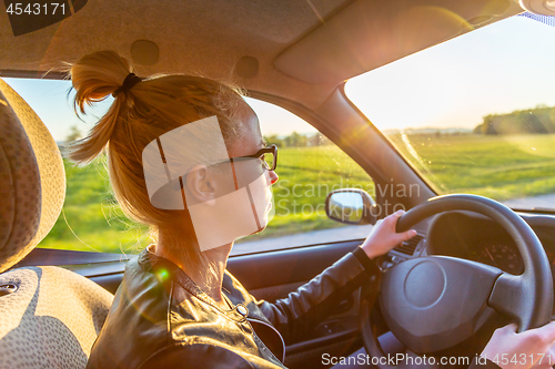 Image of Casual caucasian woman driving passenger car for a journey in countryside.