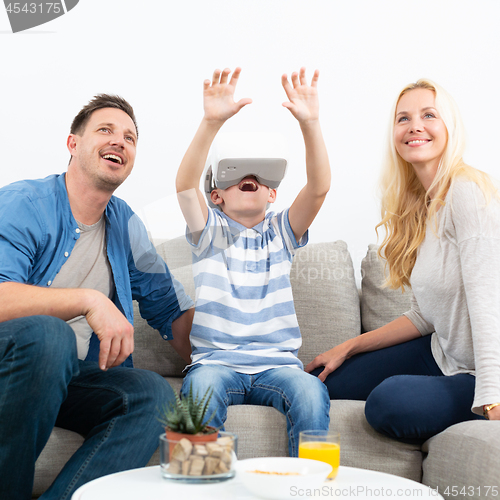 Image of Happy family at home on living room sofa having fun playing games using virtual reality headset