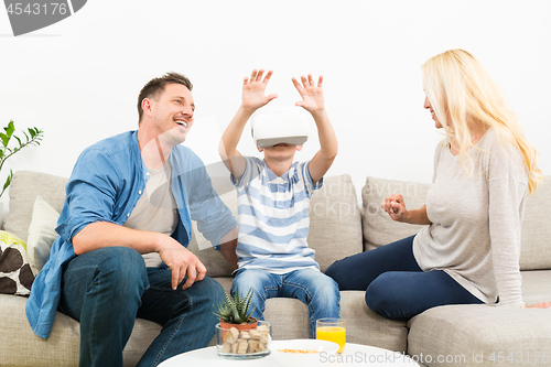 Image of Happy family at home on living room sofa having fun playing games using virtual reality headset