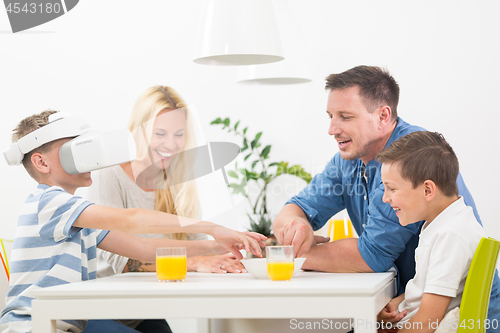 Image of Happy family at home on living room sofa having fun playing games using virtual reality headset