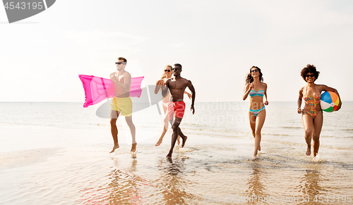 Image of friends run with beach ball and swimming mattress