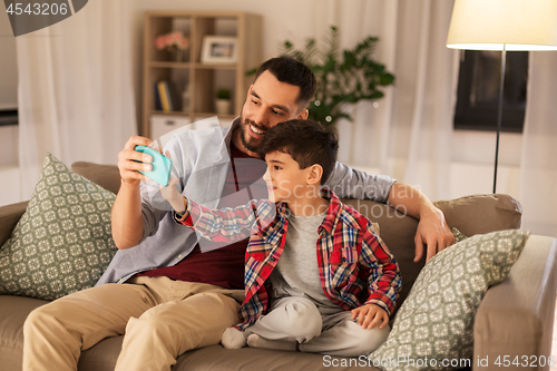 Image of father and son taking selfie at home