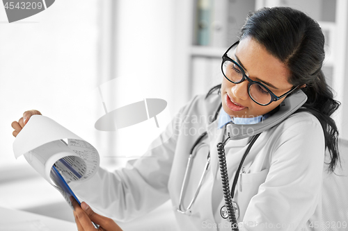 Image of doctor with clipboard calling on phone at hospital