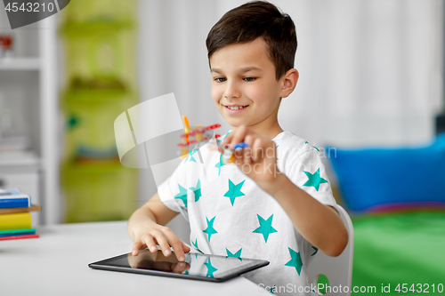 Image of boy with tablet computer and toy airplane at home