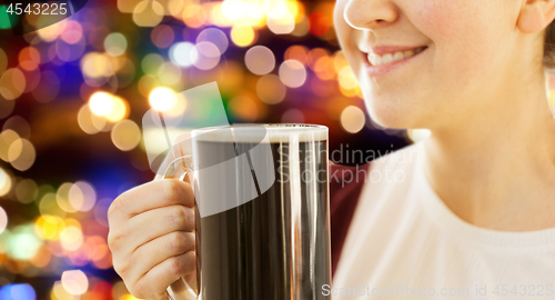 Image of close up of smiling woman with dark beer in mug