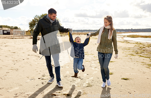 Image of happy family walking along autumn beach