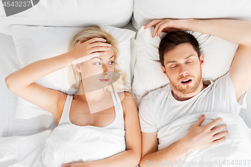 Image of unhappy woman in bed with snoring sleeping man