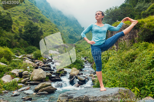 Image of Woman doing Yoga asana outdoors at waterfall