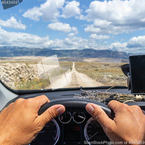 Image of Detail of male driver hands on steering wheel. Driving a car on country road. View from the cabin trough the windshield.