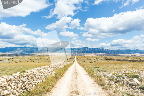 Image of Dirt road leading trough dry rocky Mediterranean coastal lanscape of Pag island, Croatia in summertime