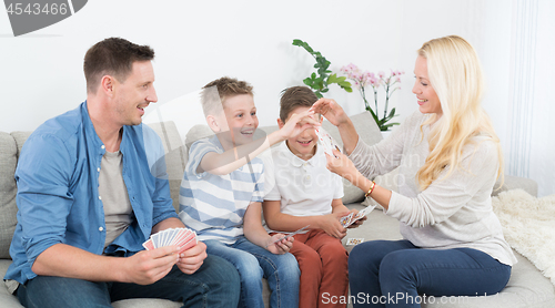 Image of Happy young family playing card game at home.