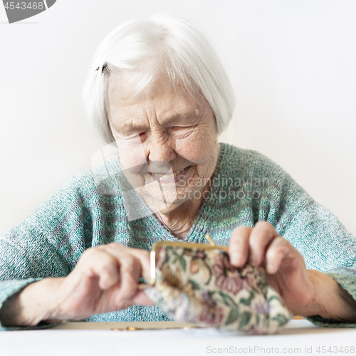 Image of Cheerful elderly 96 years old woman sitting at table at home happy with her pension savings in her wallet after paying bills.