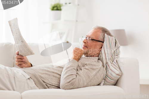 Image of senior man reading newspaper at home