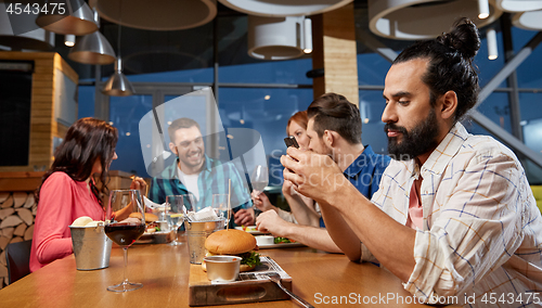 Image of man messaging on smartphone at restaurant