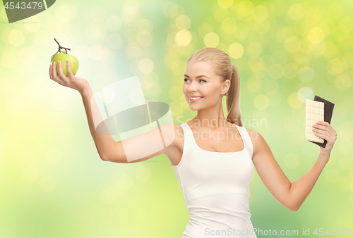 Image of woman choosing green apple instead of chocolate