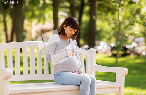 Image of happy pregnant asian woman sitting on park bench