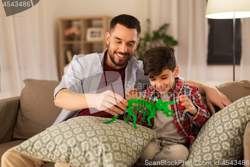 Image of father and son playing with toy dinosaur at home