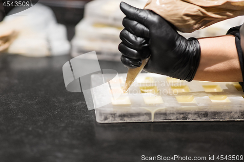 Image of confectioner filling mold by cream at pastry shop