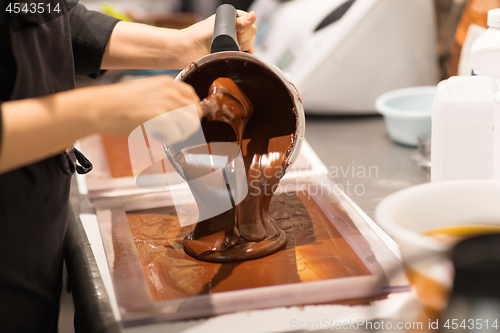 Image of confectioner makes chocolate dessert at sweet-shop