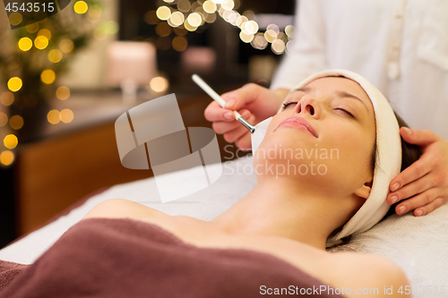 Image of beautician applying facial mask to woman at spa