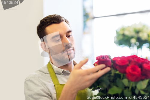 Image of florist or seller setting red roses at flower shop