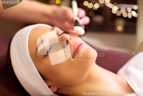 Image of beautician applying facial mask to woman at spa