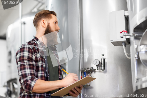 Image of man with clipboard at craft brewery or beer plant