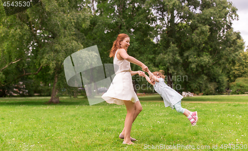 Image of happy mother playing with baby girl at summer park