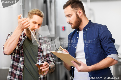 Image of men with pipette testing craft beer at brewery