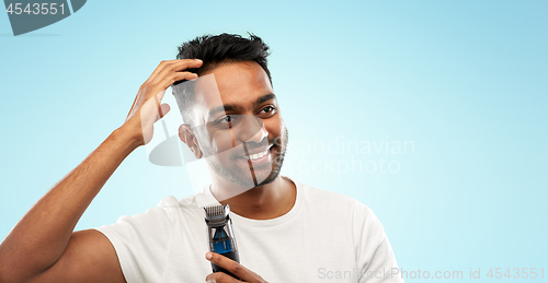 Image of smiling indian man with trimmer touching his hair