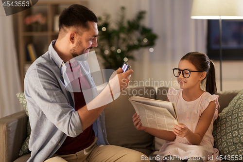 Image of father photographing daughter by cellphone at home