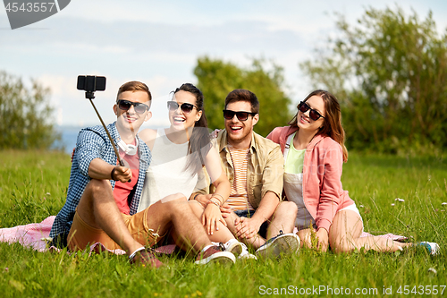 Image of friends taking picture by selfie stick in summer