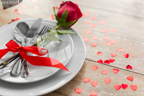 Image of close up of red rose flower on set of dishes