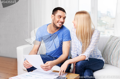 Image of couple with paper bills and calculator at home