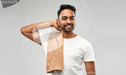 Image of smiling indian man with towel over grey background