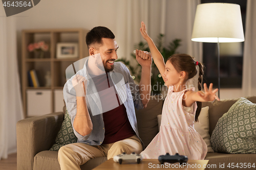 Image of father and daughter playing video game at home