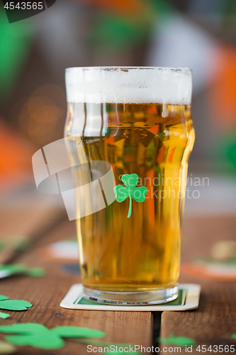 Image of close up of glass of beer with shamrock on table