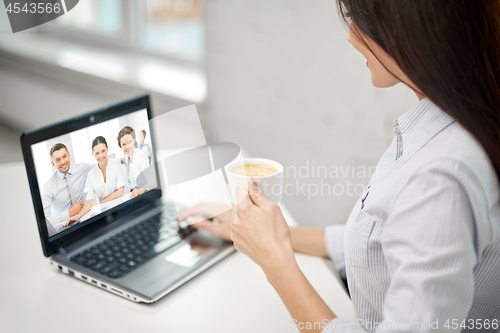 Image of woman drinking coffee and having video conference